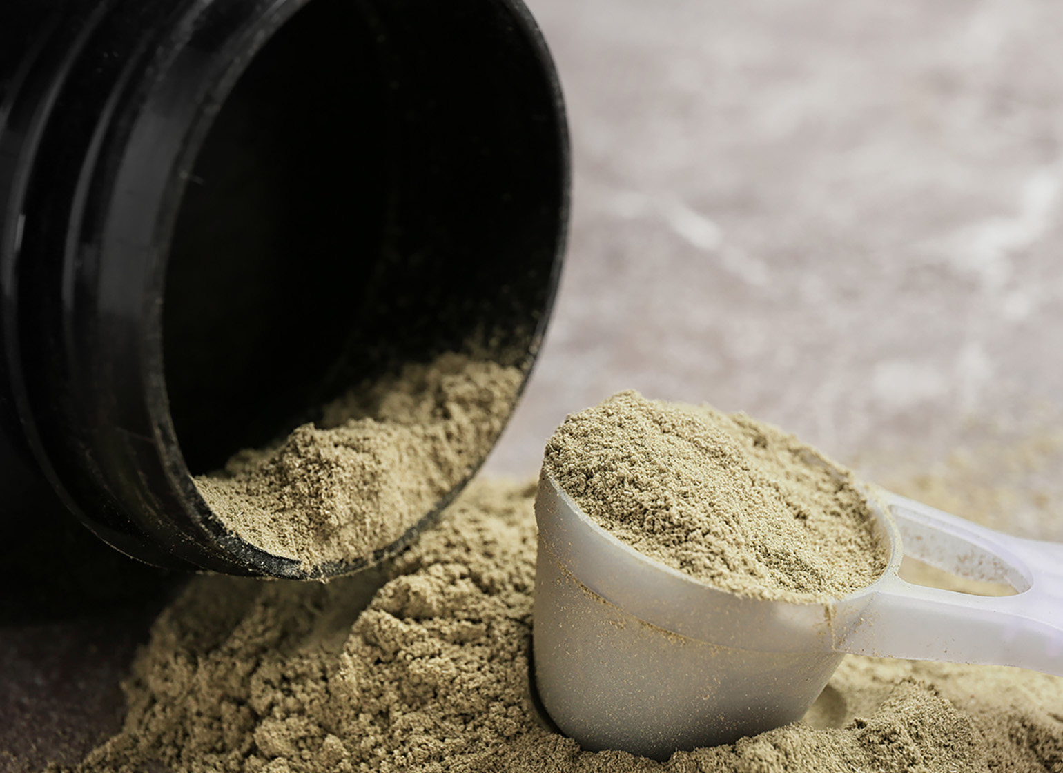 A tub of plant-based protein powder on its side with a scoop